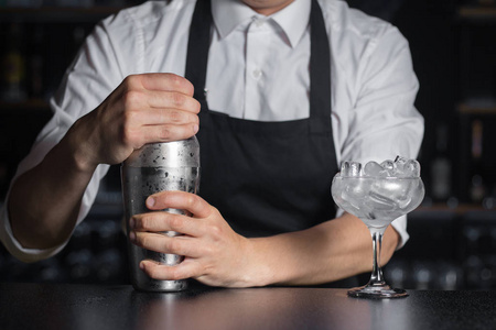 慢摇酒吧酒保 mixologist 在酒吧柜台上拿着一个冰冷的摇瓶.