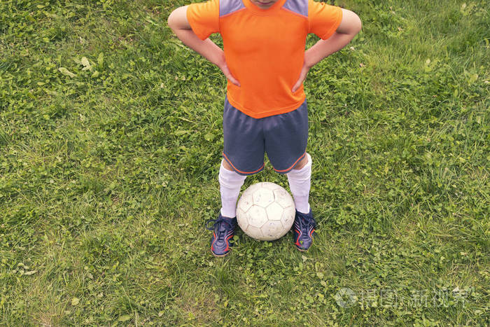 男孩的腿在绿色的草地上的球.球员准备好踢足球了.