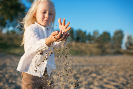快乐的小女儿的画像在沙滩上玩沙