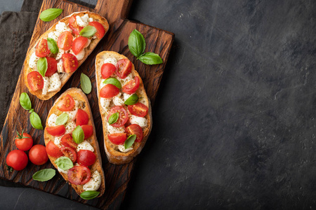 Bruschetta 与西红柿, 芝士干酪和罗勒在一个切割板上。传统的意大利开胃菜或小吃, 开胃菜来。具有复制空间的顶部视图。平