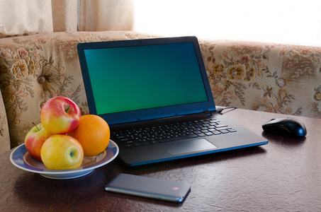打开笔记本水果盘一台智能手机放在桌子上，舒适的Ki