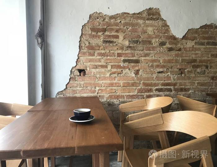 没有人在漂亮的古董咖啡店与老式砖和白色的墙壁和只有一杯热咖啡在经典的一套木制棕色桌子和椅子