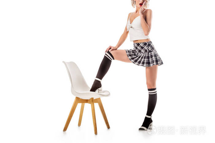 在白色的椅子上 用一条腿站在短格子裙和膝袜上的诱人女人的裁剪镜头照片 正版商用图片0sa1p0 摄图新视界
