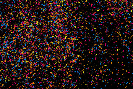 多彩的爆炸的五彩纸屑.孤立在黑色背景上的颗粒状抽象五彩的纹理.