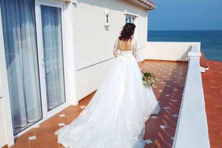 一个穿着白色婚纱的漂亮新娘正享受着在夕阳下的一座美丽拱门的篮板。良好的心情, 良好的氛围。婚礼理念