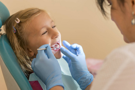 小女孩在牙医办公室的招待会上。在牙科治疗后, 小女孩坐在牙医旁边的椅子上。小女孩坐在牙医的办公室里