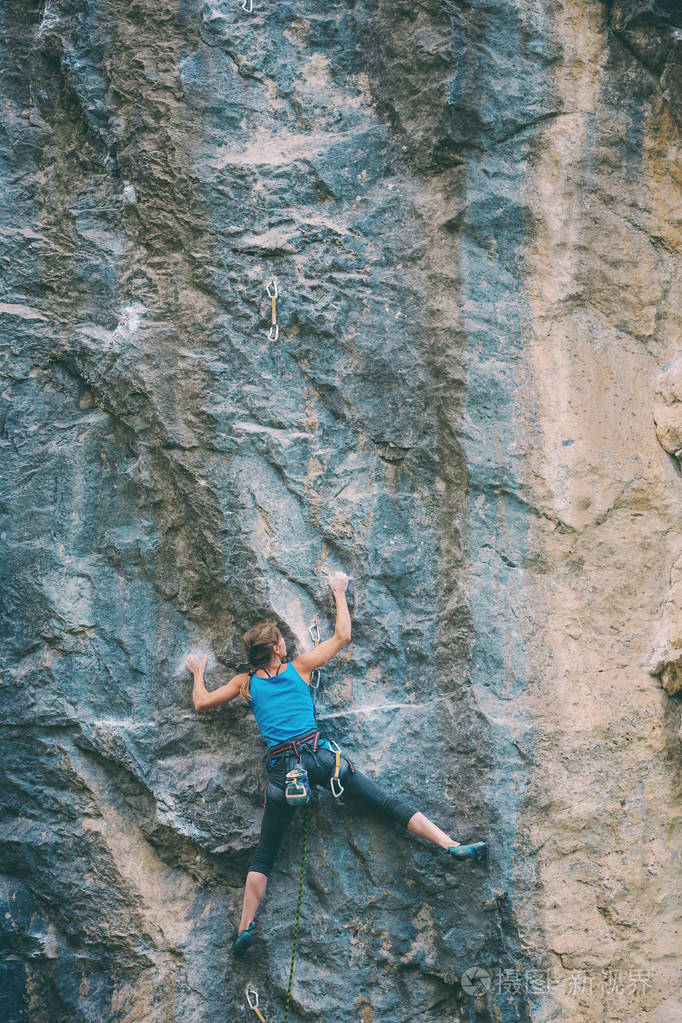 登山者正在训练攀登岩石.坚强的女孩克服了艰难的攀登路线.