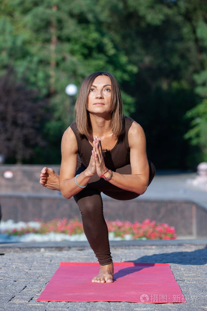 快乐的女人站在瑜伽姿势在草地上的公园.