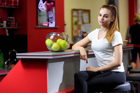 女孩坐在一碗苹果在健身房, 红色背景