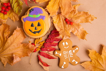 万圣节假期传统糖果。姜饼骨架的人和南瓜在秋天的叶子和牛皮纸的背景微笑。用于插入文本的背景图像