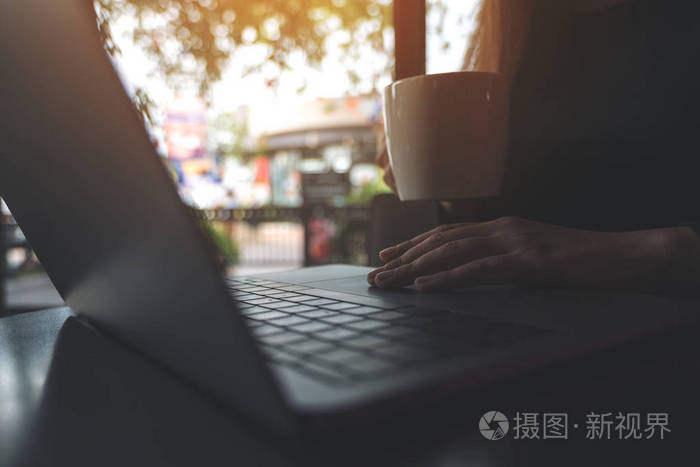 商务女性特写图像在笔记本电脑键盘上工作和打字, 同时喝咖啡