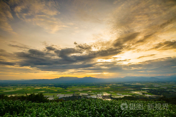 在日落的时候山在暮光之城的天空视野。在黄昏，夕阳时代背景在稻田里的天空