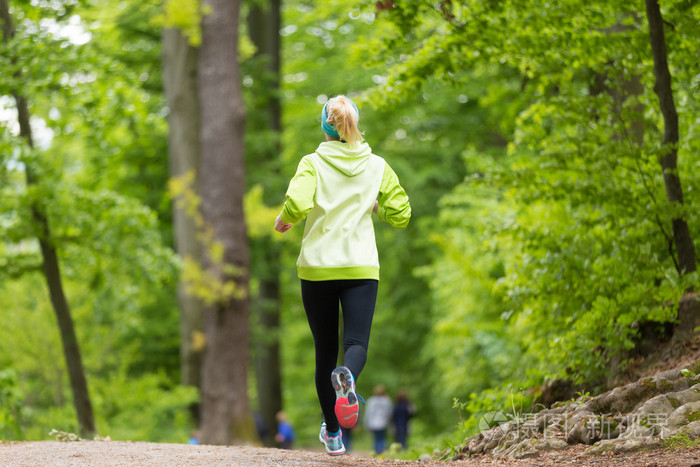 运动年轻的女性跑步者在森林里