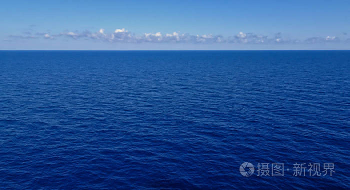 非常平静的深蓝海洋与一些云彩和浅蓝色天空在地平线上