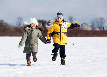 两个年幼的孩子在雪地上奔跑, 双手微笑着