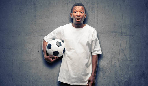 非洲黑人男子拿着足球吓得发抖, 表示恐慌和恐惧