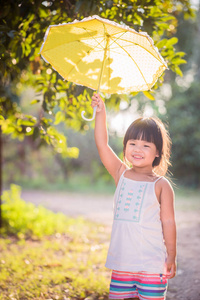 快乐的小女孩, 雨伞在阳光明媚的日子里漫步在公园里