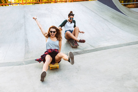 两个欢快的年轻女孩玩滑板在公园