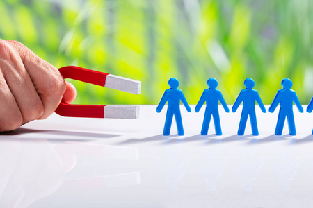 磁铁举行商人的手吸引蓝人的身影站在一排马蹄磁铁照片