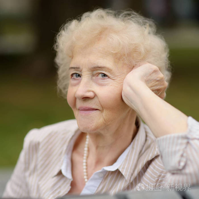 户外画像的美丽的资深妇女与卷曲的白发.在公园放松的老夫人