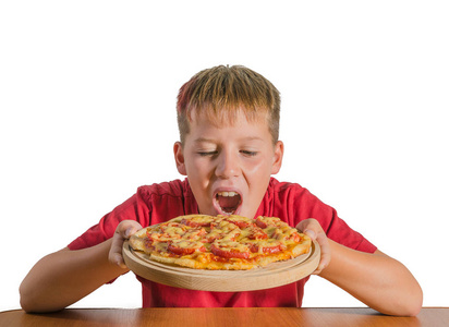 少年拿着一个比萨饼在他的手上的木板