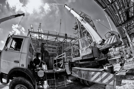 扩张腿的卡车起重机和扩展的景气在石化复合体的新的工厂的建筑工地。黑白照片