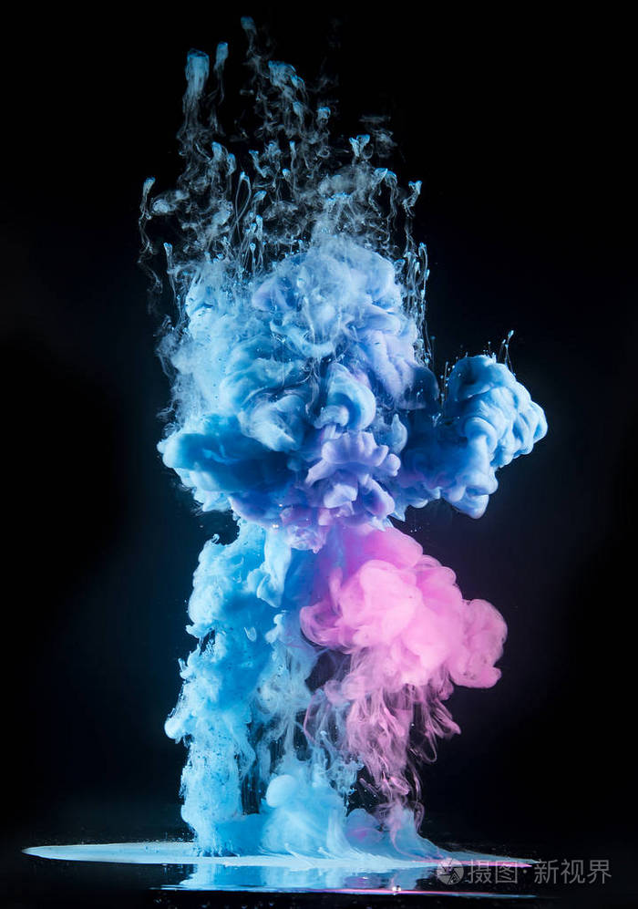 五颜六色的彩虹颜料从上面的水中混合而出.水下旋转墨水