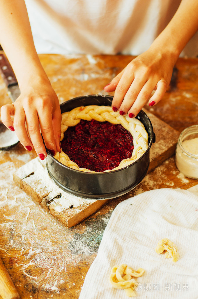 烹饪自制覆盆子蛋糕.轧制做馅饼的面团的女人