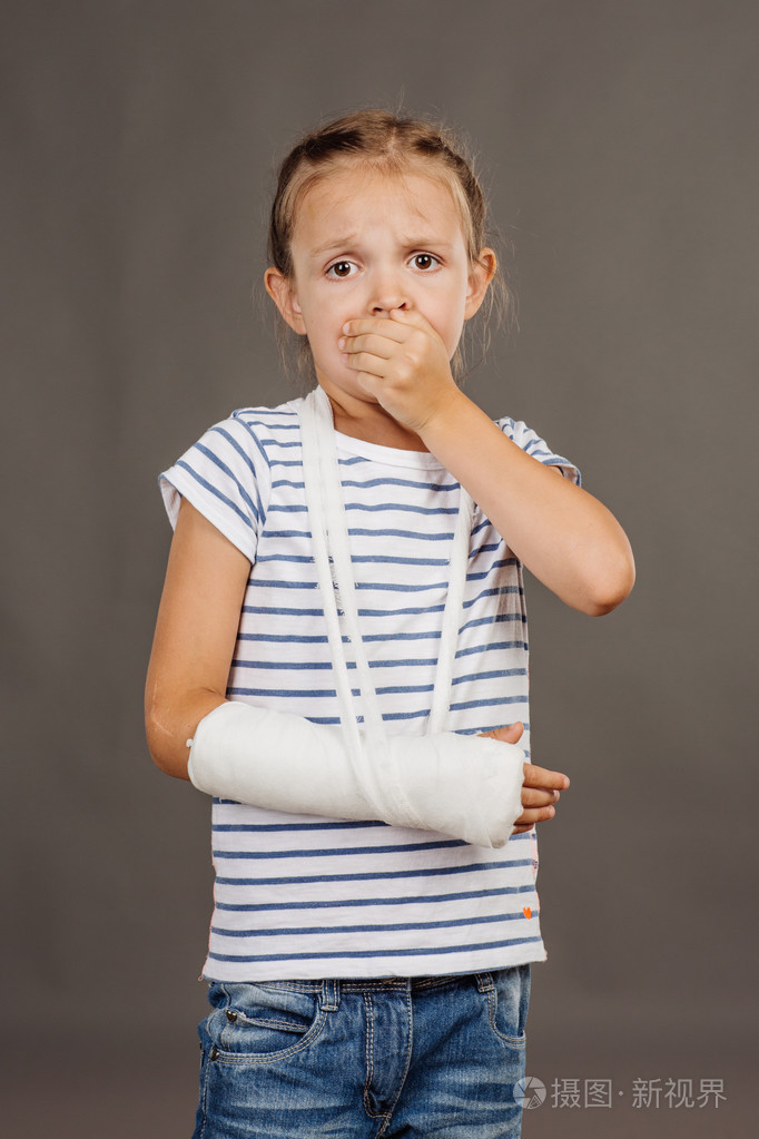 用断胳膊心疼的女孩正站在灰色的背景上