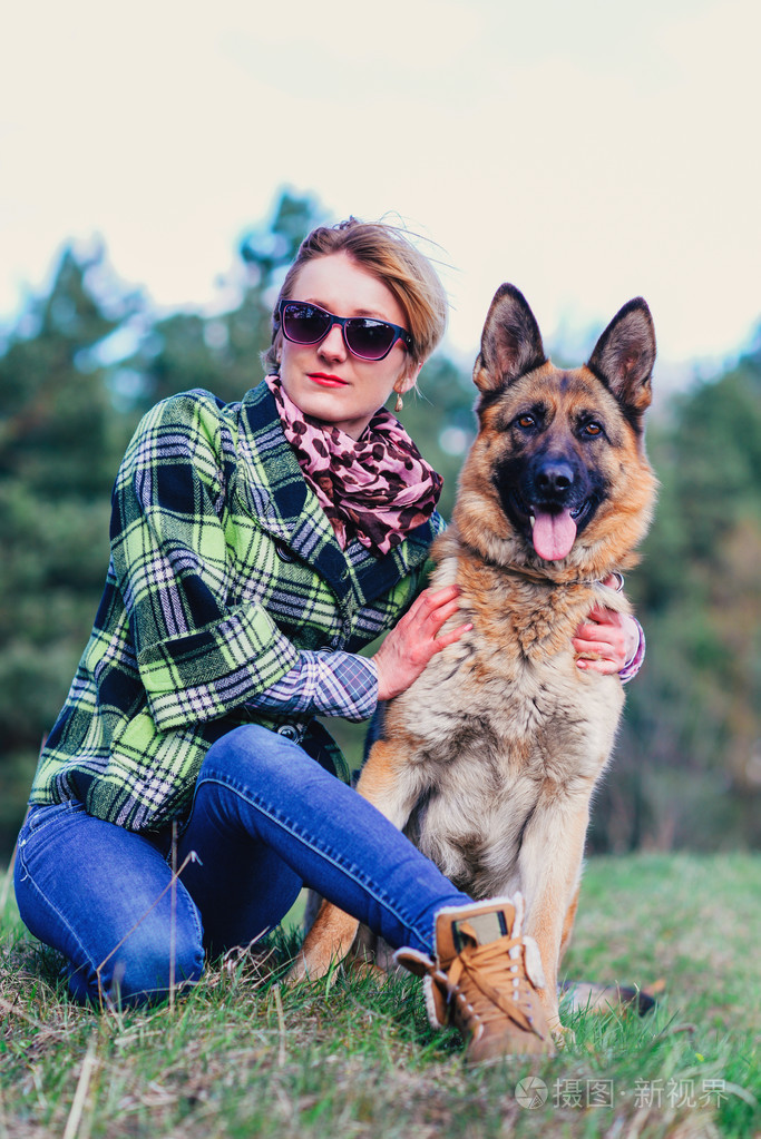 德国牧羊犬和漂亮女孩在森林里玩