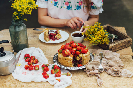 女人吃美味的自制蛋糕与 aisheny 和毛绒的草莓甜点.夏天的风格餐桌.