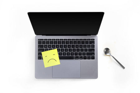 桌面与笔记本电脑的顶部视图, 张贴在白色背景悲伤的脸和勺子的音符