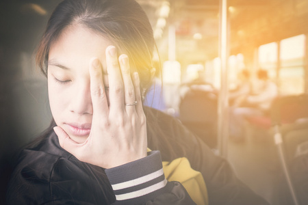 日本女孩在火车上有头疼得厉害。上下班公交车上有晕车的亚洲女性