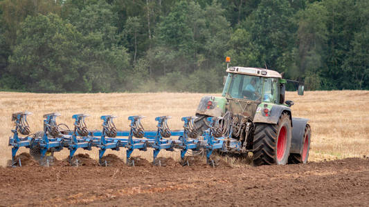 拖拉机用犁对待土壤。从后面查看