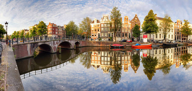 美丽的阿姆斯特丹日落。荷兰春天的桥梁和运河上的典型老荷兰房子
