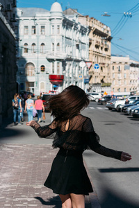 美丽的黑发旋风, 在城市中间的街道上跳舞, 笑, 笑, 快乐, 乐趣
