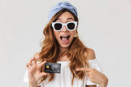 时尚快乐的女人的肖像20s 戴着太阳镜微笑着, 显示了白色背景下的信用卡隔离