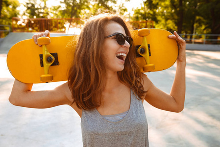 年轻快乐开朗的女人的照片走在户外滑板