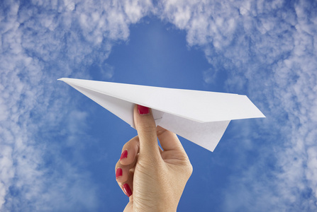 手拿纸飞机手拿着纸飞机的天空背景上照片