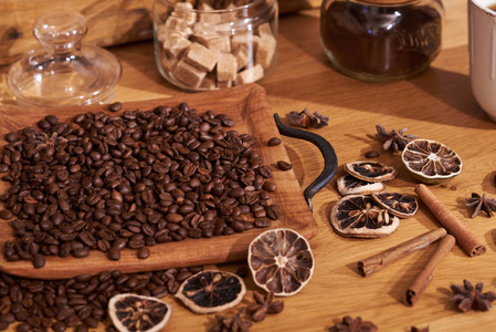 黑色烤咖啡豆与香料和糖旁边的老木箱, 和陶瓷杯新鲜的咖啡在棕色纹理背景