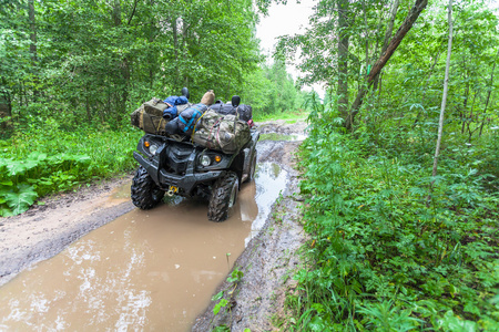 脏的 Atv 站立袋与森林道路上泥泞的水坑里的东西