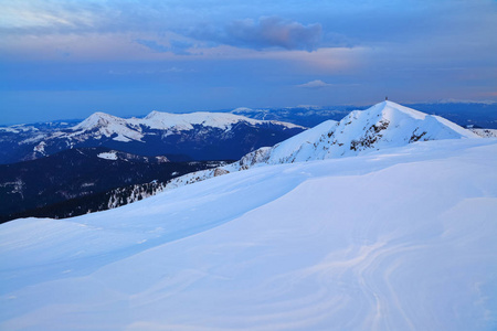 山顶上覆盖着冰雪, 上面是蓝色的阴影, 天空覆盖着蓬松的云层。冬季纹理背景