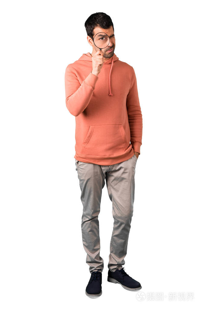 在粉红色的运动衫的男子全身, 采取放大镜, 并在孤立的白色背景看通过