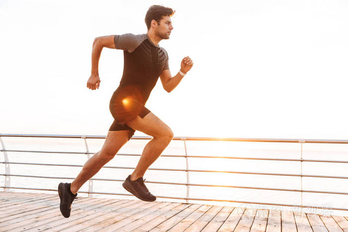 运动年轻人的形象20s 穿着短裤和 t恤衫沿着码头或海滨人行道在清晨