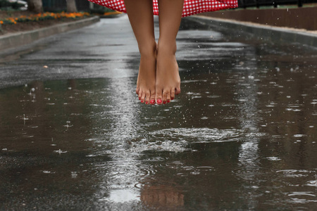 夏季雨后, 女孩的脚在水坑里跳舞的特写