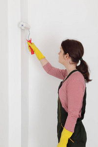 用漆辊工具画墙到白色的女工人