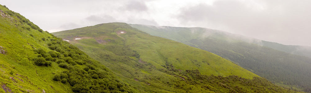 锐利的绿色山峰和戏剧性云景观的天空