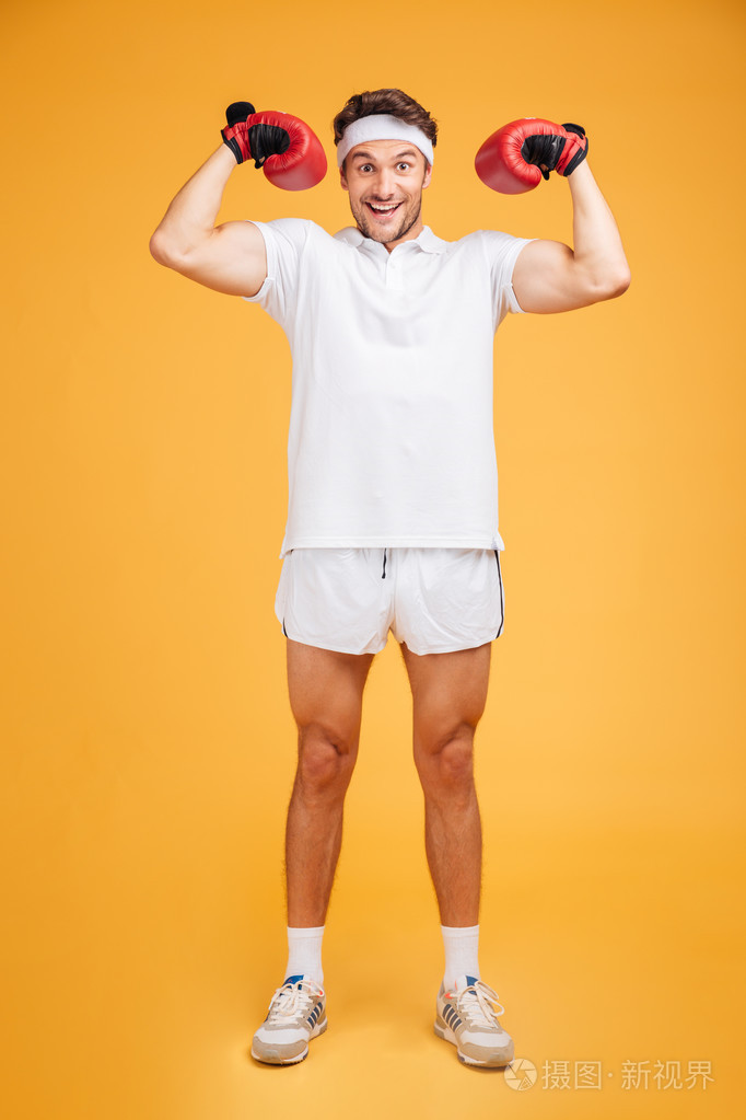 戴红手套的开朗的拳击手微笑着展示二头肌