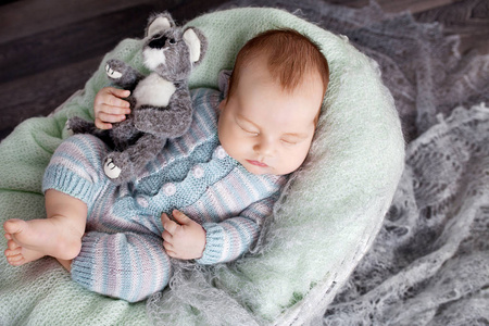 可爱的新生宝宝睡在篮子里。美丽的新生男孩与熊玩具