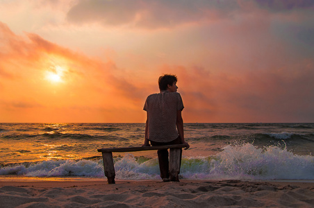 寂寞的人放松享受日落海滩上的长凳上